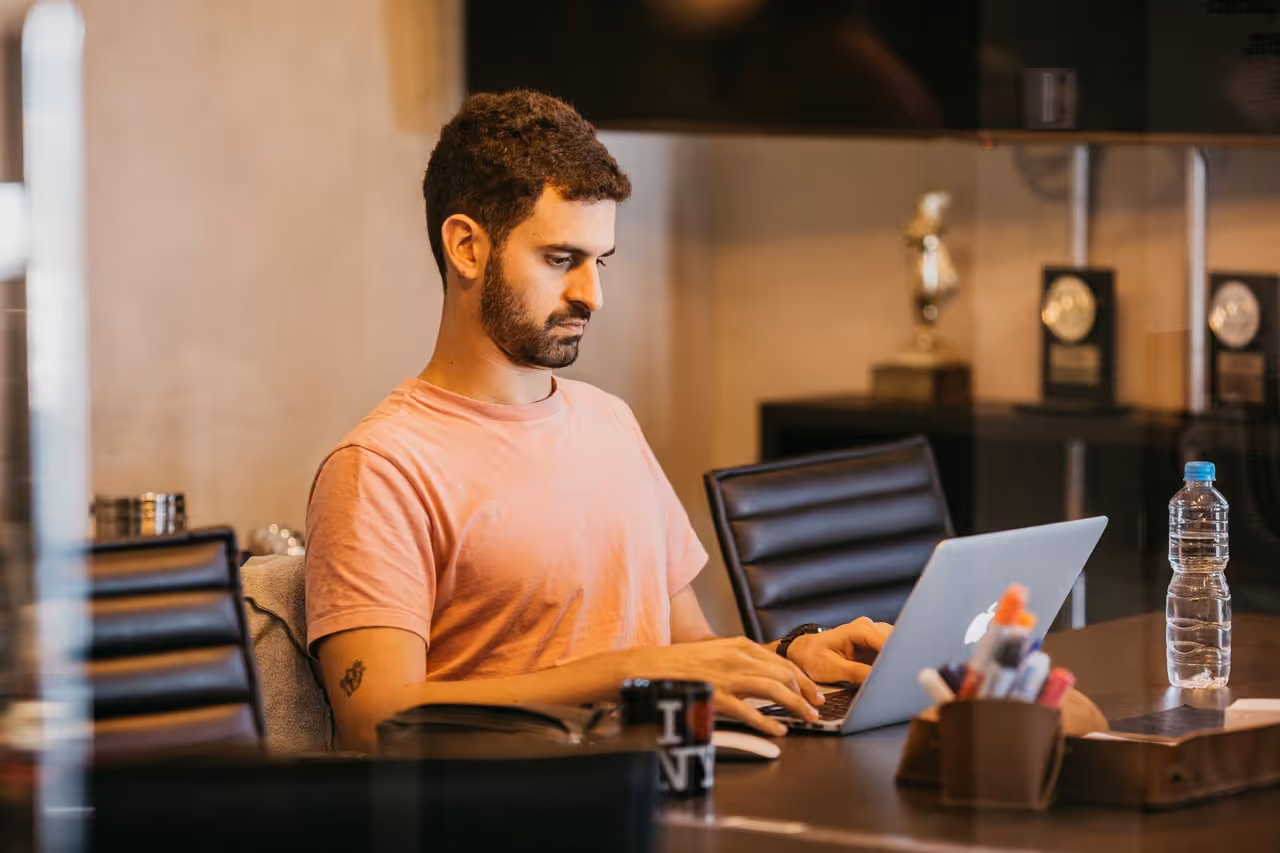 Empreendedor brasileiro trabalhando em notebook em home office, representando o público-alvo do Asaas: PMEs, MEIs e autônomos