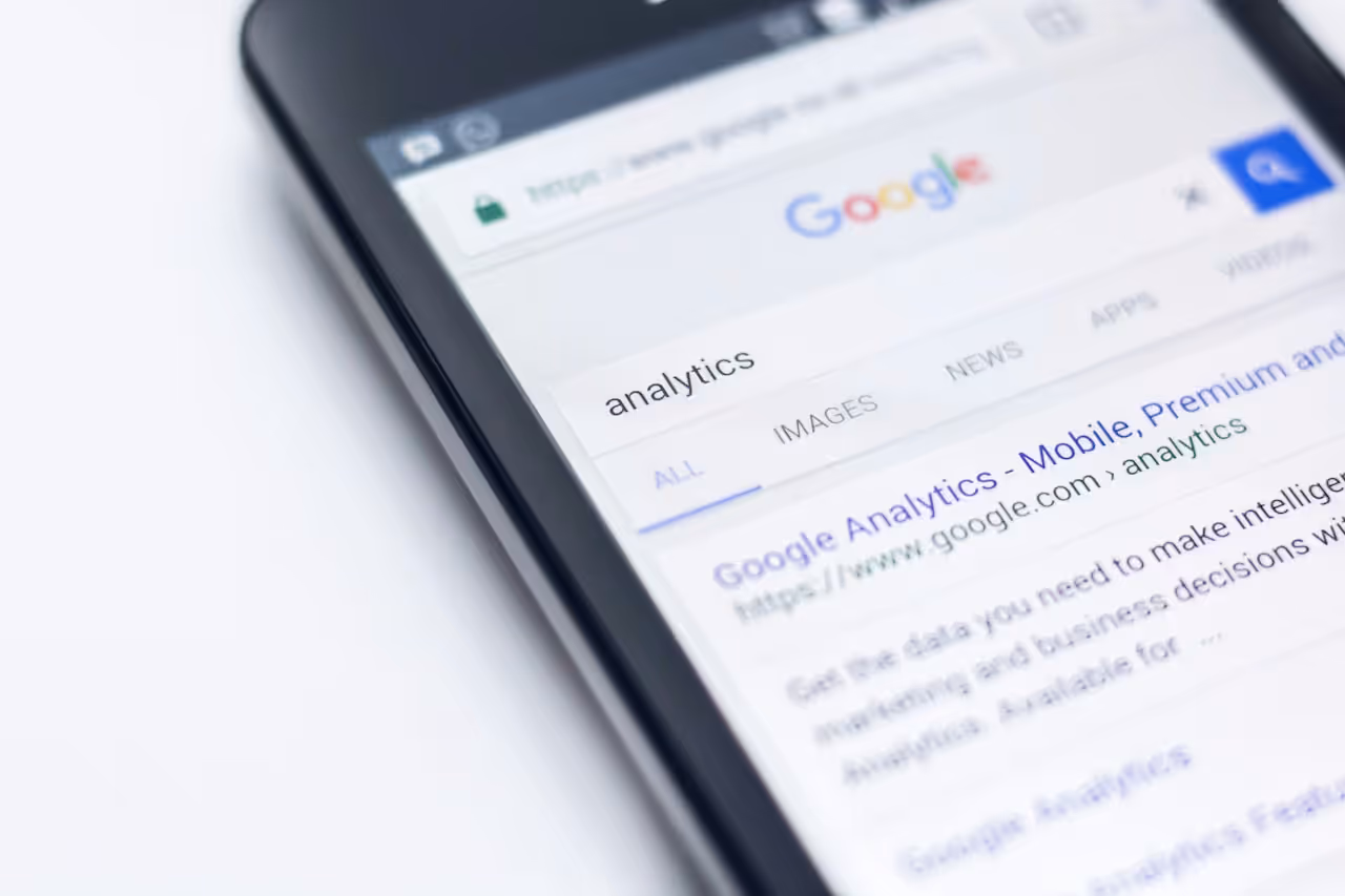 Smartphone com tela de busca do Google e resultado do Google Analytics representando pesquisa mobile em 2026