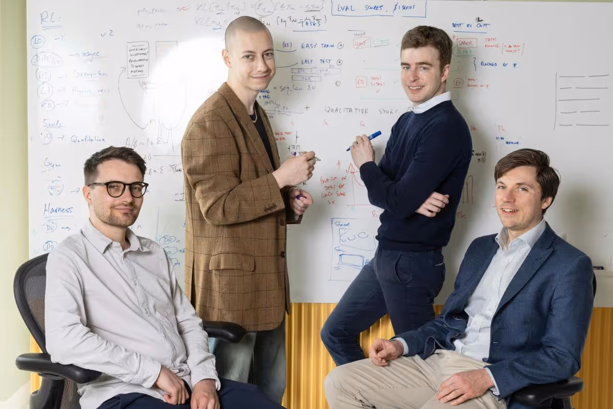 Quatro integrantes da Inherent em escritório diante de quadro com anotações de pesquisa em IA