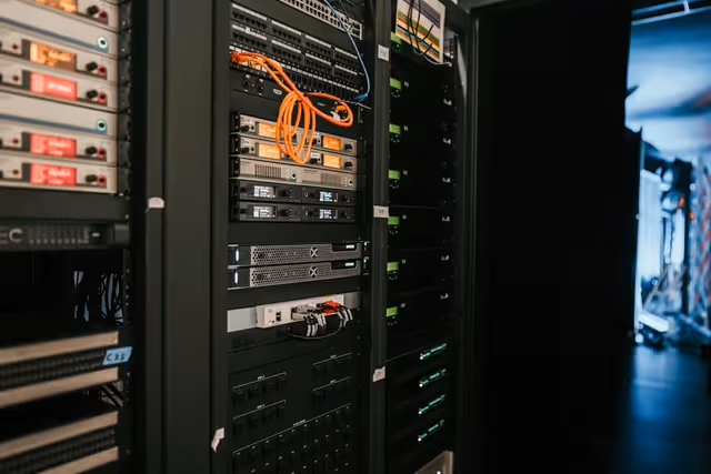 servidores em rack em data center escuro com cabos de rede iluminados representando infraestrutura de hospedagem de sites